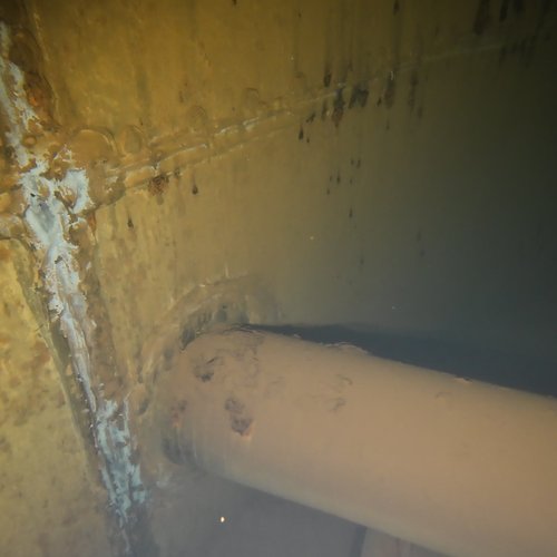 Sprinklertank-Inspektion: Stahltank, 25 Jahre – Inspektionsaufnahme Rohrschelle Ecke Sedimentablagerungen Bodensicht